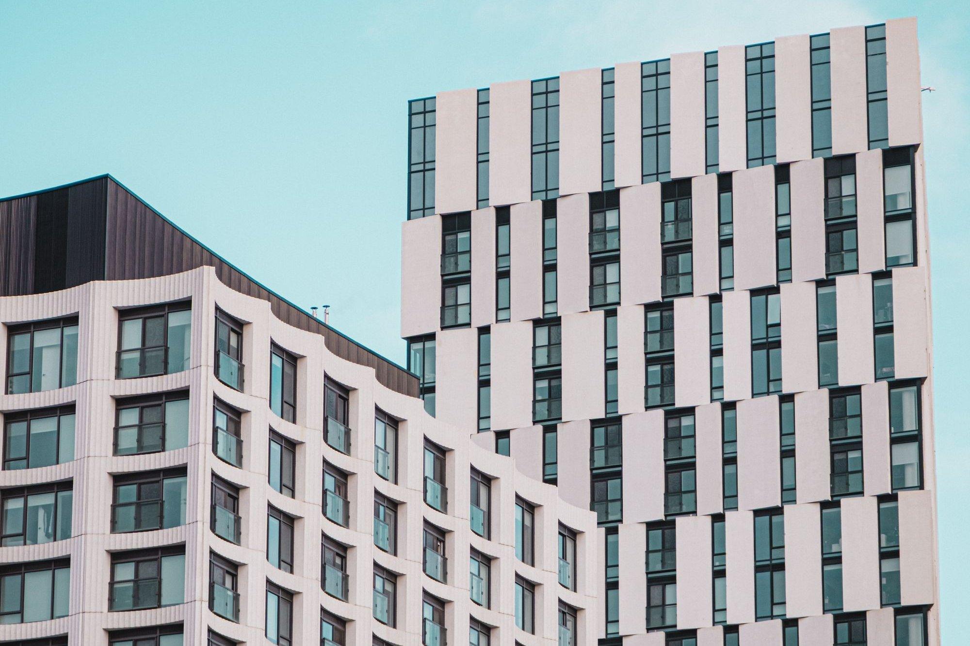 Two modern residential condominium towers in Toronto with rows of balconies and windows against a clear blue sky