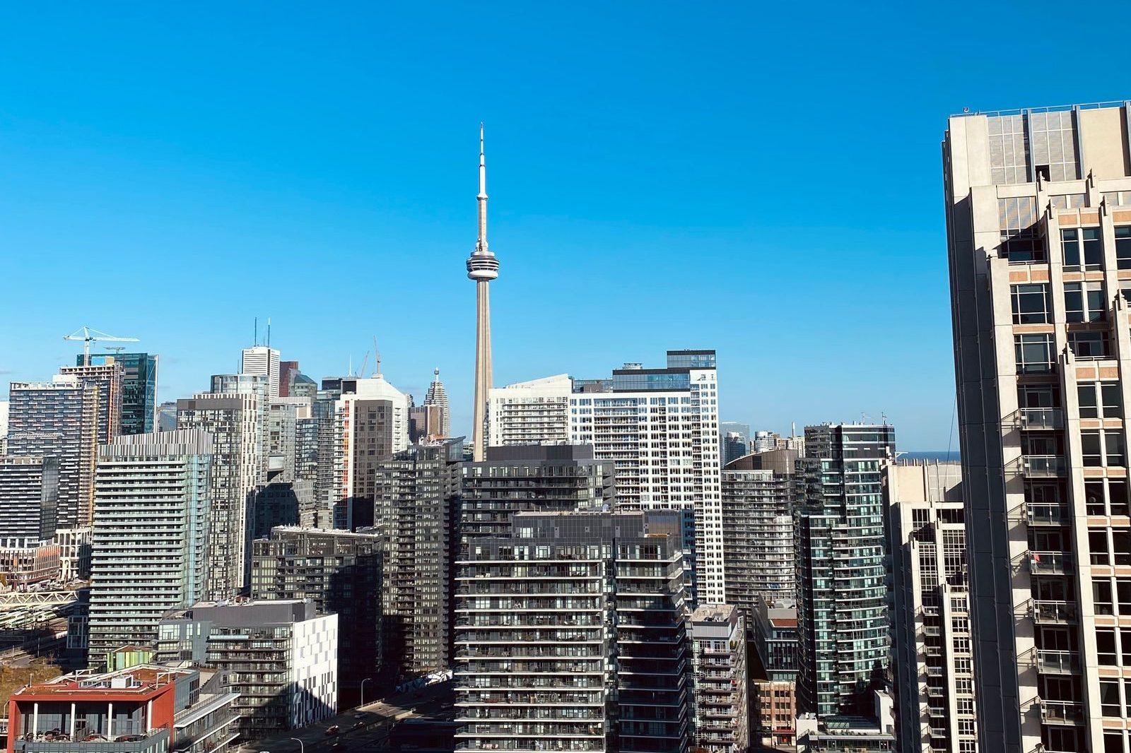Downtown Toronto condo and office towers with the CN Tower under a clear blue sky